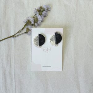 Pendientes compuesto por dos semi círculos, uno blanco y otro negro, ambos con brillantina en color plata