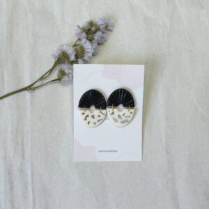 Pendientes de dos piezas enlazadas, con forma de semicírculo, una de color negro y otra de color blanca con papel de oro plata