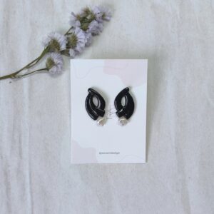 Pendientes de forma ovalada con hueco central, en color negro, con colgante de perla
