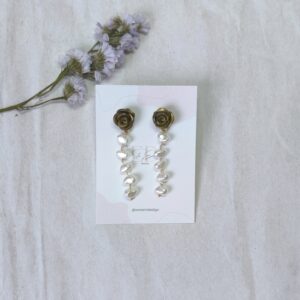 Pendientes, en forma de colgante, compuestos de una rosa en color oro, hecha a mano pétalo a pétalo, seguida de 5 perlas, enlazadas manualmente