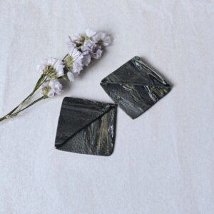 Marcapáginas en colores negro, gris, blanco, dorado, efecto mármol con textura cuero, su forma es cuadrada
