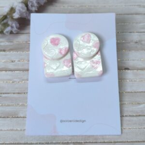 Dos piezas corazones, pieza circular seguida de una piezas cuadrada ambas en color blanco con detalles de corazones en color rosa